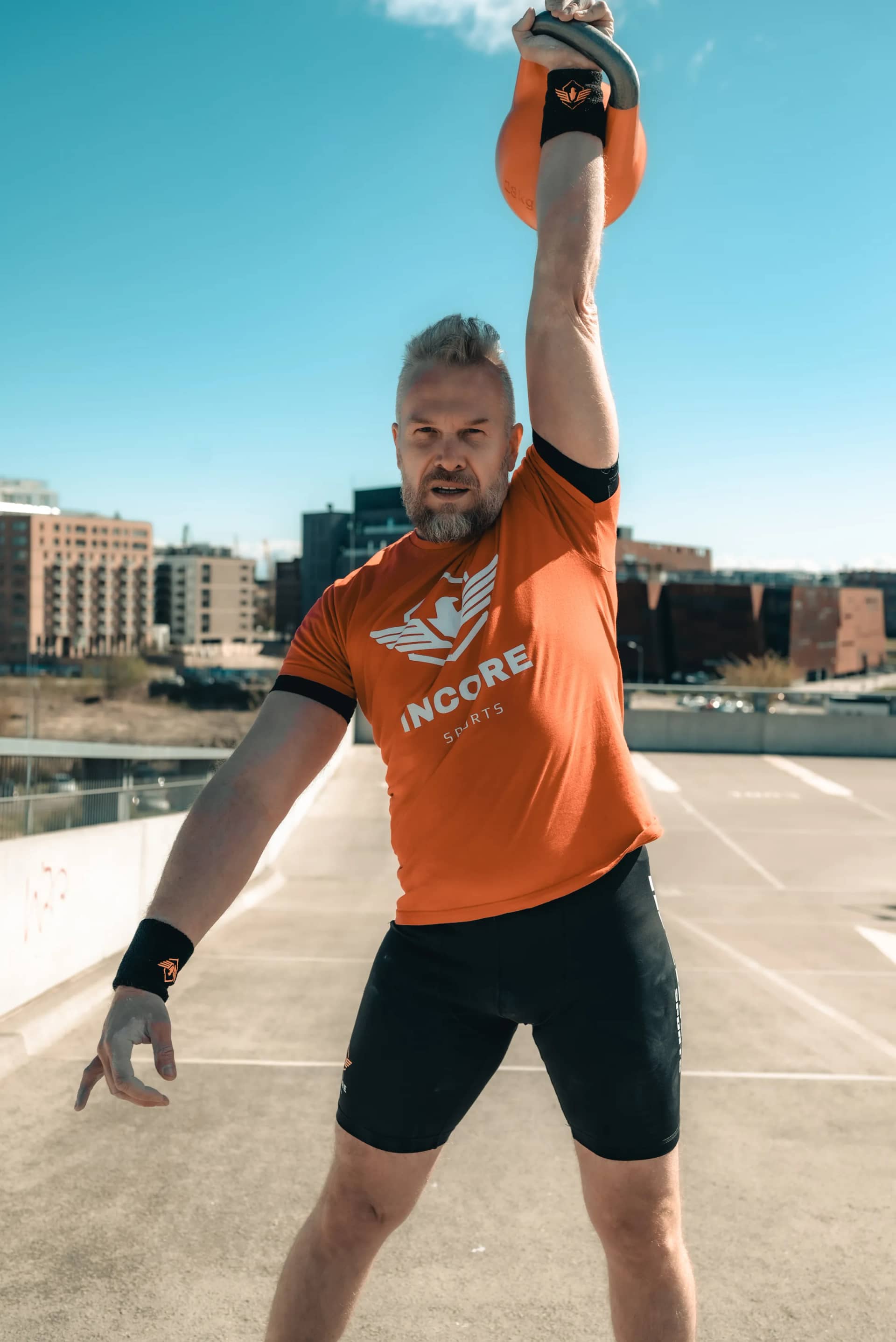 Athlete performing an overhead kettlebell press in Incore Sports apparel